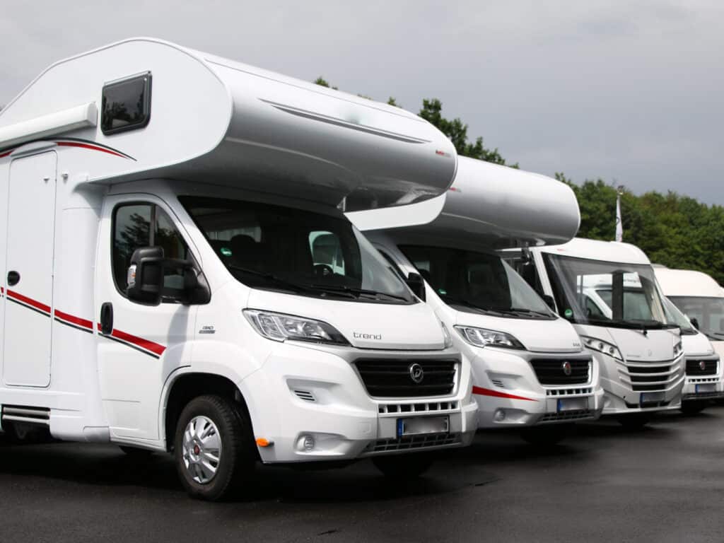 Wohnwägen bzw. Caravans in verschiedenen Größen stehen nebeneinander auf einem Parkplatz.